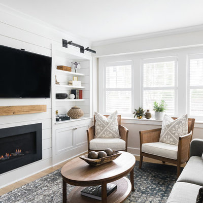Example of a small classic open concept medium tone wood floor family room design in Boston with white walls, a standard fireplace, a wood fireplace surround and a wall-mounted tv