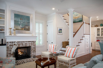 This is an example of a medium sized coastal open plan games room in Charleston with white walls, a standard fireplace, a brick fireplace surround and medium hardwood flooring.