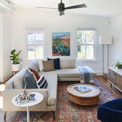 Example of a mid-sized trendy open concept medium tone wood floor and brown floor family room design in Austin with no fireplace, a wall-mounted tv and white walls