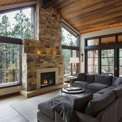 Inspiration for a rustic dark wood floor family room remodel in Albuquerque with beige walls, a standard fireplace, a stone fireplace and no tv