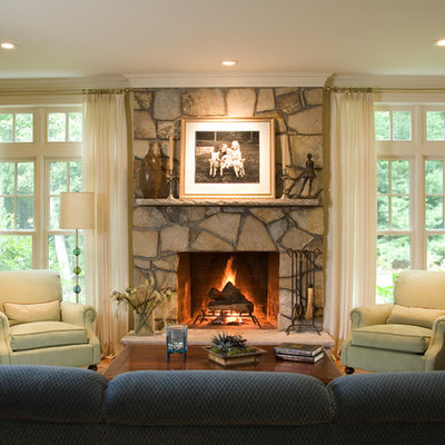 Inspiration for a large timeless enclosed medium tone wood floor and brown floor family room remodel in Boston with a stone fireplace, beige walls and a standard fireplace