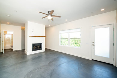 Example of a mid-sized minimalist open concept concrete floor and gray floor family room design in San Francisco with white walls, a standard fireplace, a plaster fireplace and no tv