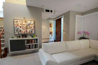 Ejemplo de sala de estar contemporánea de tamaño medio con paredes grises, suelo de baldosas de cerámica, chimenea lineal, marco de chimenea de piedra, televisor retractable y suelo blanco