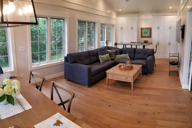 Imagen de sala de estar abierta costera con suelo de madera clara