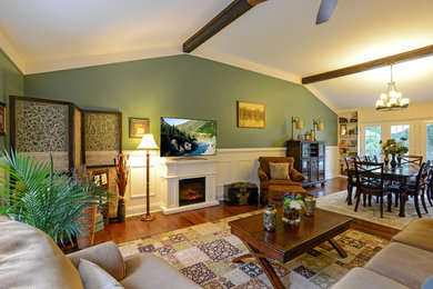 Imagen de sala de estar abierta clásica grande con paredes verdes, suelo de madera en tonos medios, todas las chimeneas, marco de chimenea de madera, suelo marrón y televisor independiente