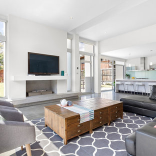 Inspiration for a contemporary family room in Melbourne with white walls, concrete floors, a ribbon fireplace, a wall-mounted tv and grey floor.