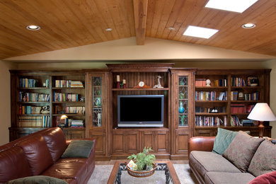 Modelo de sala de estar con biblioteca cerrada mediterránea de tamaño medio con paredes beige, suelo de madera en tonos medios y pared multimedia