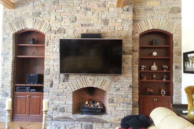 Imagen de sala de estar abierta mediterránea de tamaño medio con paredes blancas, suelo de madera clara, chimenea lineal, marco de chimenea de piedra y televisor colgado en la pared