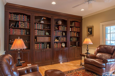Foto di un grande soggiorno classico chiuso con libreria, pareti marroni, parquet chiaro e parete attrezzata