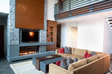 Inspiration for a large contemporary open plan games room in Vancouver with beige walls, a ribbon fireplace, a built-in media unit, light hardwood flooring and a concrete fireplace surround.