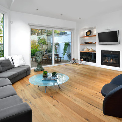 Inspiration for a contemporary open concept light wood floor and beige floor family room remodel in Toronto with white walls, a standard fireplace and a wall-mounted tv