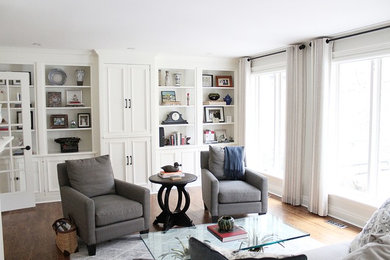Großes, Offenes Klassisches Wohnzimmer mit grauer Wandfarbe, braunem Holzboden, Kamin, Kaminumrandung aus Backstein und verstecktem TV in Toronto