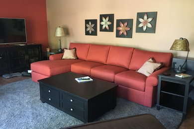Imagen de sala de estar abierta clásica renovada de tamaño medio con paredes rojas, suelo de madera oscura, estufa de leña y televisor independiente