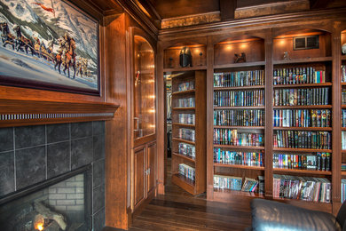 Inspiration for a mid-sized transitional enclosed dark wood floor family room library remodel in Omaha with brown walls, a standard fireplace and a tile fireplace
