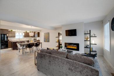 Example of a small trendy open concept light wood floor family room design in Edmonton with white walls, a standard fireplace and a wall-mounted tv