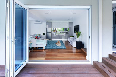 Foto de sala de estar abierta contemporánea grande sin chimenea con paredes blancas, suelo de madera en tonos medios, televisor colgado en la pared y suelo marrón