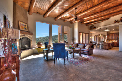 Large southwest open concept porcelain tile family room photo in Albuquerque with beige walls, a corner fireplace, a stone fireplace and no tv