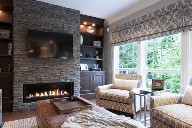 Family room - large traditional medium tone wood floor family room idea in Vancouver with a stone fireplace, gray walls, a ribbon fireplace and a wall-mounted tv