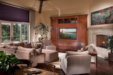 Example of a classic dark wood floor family room design in Orange County with beige walls, a corner fireplace, a stone fireplace and a media wall