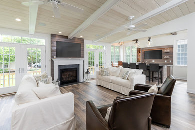 Large farmhouse open plan games room in Philadelphia with white walls, a standard fireplace, a wooden fireplace surround, a wall mounted tv, brown floors and medium hardwood flooring.
