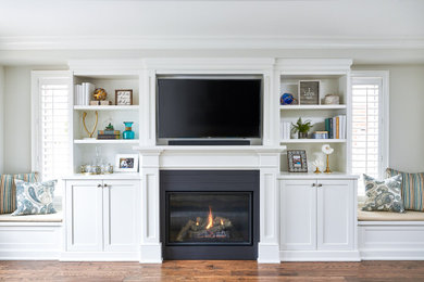Example of a mid-sized classic open concept medium tone wood floor and brown floor family room design in Toronto with gray walls, a standard fireplace, a wood fireplace surround and a media wall