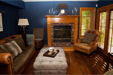Foto på ett mellanstort amerikanskt allrum med öppen planlösning, med blå väggar, mörkt trägolv, en standard öppen spis, en spiselkrans i tegelsten och flerfärgat golv