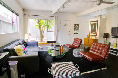 Ejemplo de sala de estar abierta bohemia de tamaño medio sin chimenea con paredes blancas, suelo de cemento y televisor colgado en la pared