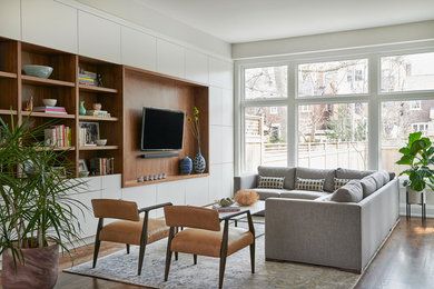 Foto de sala de estar con biblioteca abierta escandinava sin chimenea con paredes blancas, suelo de madera en tonos medios y pared multimedia