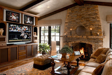 Inspiration for a medium tone wood floor family room remodel in Los Angeles with beige walls, a standard fireplace, a stone fireplace and a media wall