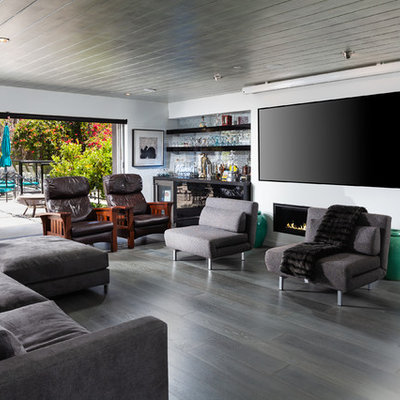 Family room - mid-sized contemporary enclosed dark wood floor and gray floor family room idea in Orange County with white walls, a wall-mounted tv, a bar, a ribbon fireplace and a metal fireplace