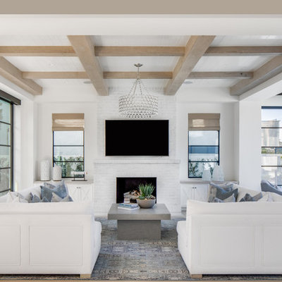 Family room - coastal open concept light wood floor family room idea in Orange County with white walls, a standard fireplace, a brick fireplace and a wall-mounted tv