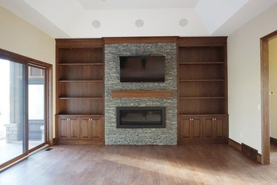 Inspiration for a large timeless enclosed medium tone wood floor and brown floor family room remodel in Toronto with a stone fireplace