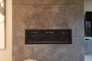 ポートランドにある高級な中くらいなコンテンポラリースタイルのおしゃれなオープンリビング (ベージュの壁、淡色無垢フローリング、漆喰の暖炉まわり、据え置き型テレビ、茶色い床) の写真