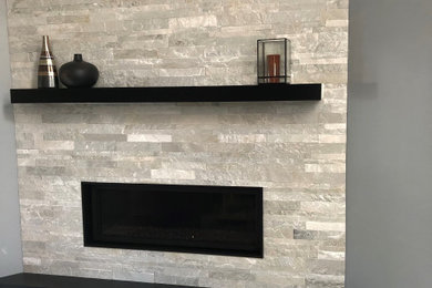 Imagen de sala de estar abierta tradicional renovada de tamaño medio con paredes grises, moqueta, chimenea lineal, marco de chimenea de piedra y suelo gris