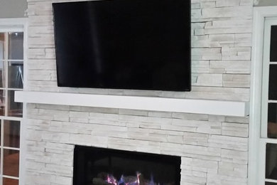 Modernes Wohnzimmer mit weißer Wandfarbe, dunklem Holzboden, Gaskamin, Kaminumrandung aus Stein und TV-Wand in Atlanta