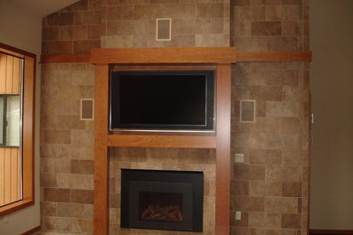 Example of a large transitional medium tone wood floor family room design in Seattle with a tile fireplace, a wall-mounted tv, beige walls and a standard fireplace