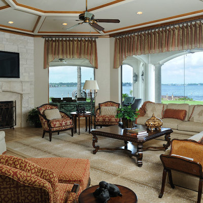 Family room - mediterranean enclosed medium tone wood floor family room idea in Houston with beige walls, a standard fireplace, a stone fireplace and a wall-mounted tv