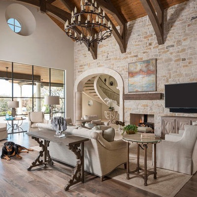 Family room - huge mediterranean medium tone wood floor family room idea in Dallas with a standard fireplace, a stone fireplace and a wall-mounted tv