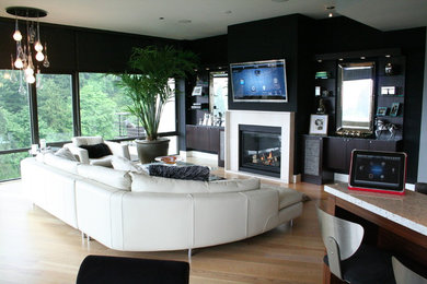 Diseño de sala de estar contemporánea con paredes negras, suelo de madera clara y televisor colgado en la pared