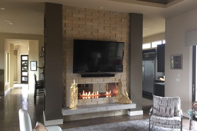 Mid-sized trendy open concept slate floor family room photo in Austin with gray walls, a two-sided fireplace, a stone fireplace and a wall-mounted tv