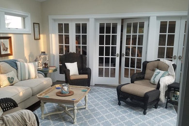 Imagen de sala de estar abierta costera de tamaño medio sin chimenea y televisor con paredes beige, suelo de madera oscura y suelo marrón