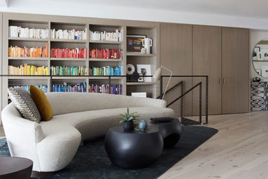 Ejemplo de sala de estar con biblioteca abierta actual sin chimenea y televisor con paredes blancas, suelo de madera clara y suelo beige