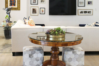 Modelo de sala de estar abierta moderna extra grande con paredes blancas, suelo de madera clara, televisor colgado en la pared y suelo gris