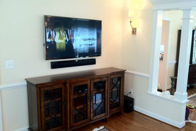 This is an example of a traditional games room in DC Metro with yellow walls, medium hardwood flooring, no fireplace and a wall mounted tv.