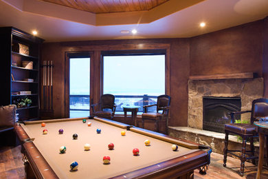 This is an example of a medium sized traditional enclosed games room in Orlando with a game room, brown walls, dark hardwood flooring, a standard fireplace and a stone fireplace surround.