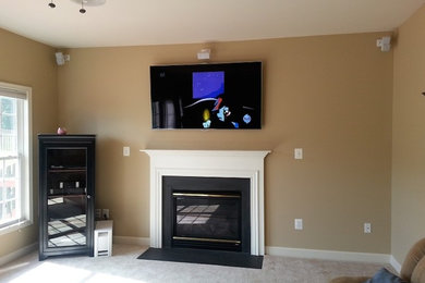 Foto de sala de estar tradicional con paredes beige, moqueta, todas las chimeneas y televisor colgado en la pared