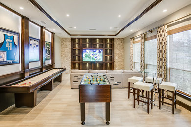 Imagen de sala de juegos en casa cerrada actual grande sin chimenea con paredes beige, suelo de madera clara, pared multimedia y suelo beige