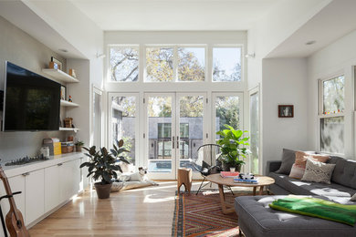 Mittelgroßes, Offenes Skandinavisches Wohnzimmer ohne Kamin mit weißer Wandfarbe, hellem Holzboden und TV-Wand in Austin