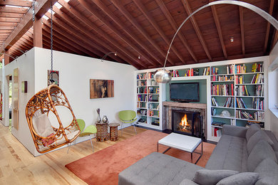 Modelo de sala de estar abierta minimalista pequeña con paredes blancas, suelo de madera en tonos medios, todas las chimeneas, marco de chimenea de piedra y televisor independiente