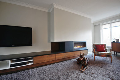 Large trendy enclosed dark wood floor family room photo in Toronto with a ribbon fireplace, a stone fireplace, a wall-mounted tv and white walls